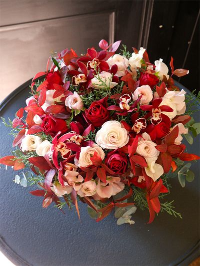 デンタルクリニックの院長の誕生日の贈り花ですが、クリスマスの雰囲気で、とのオーダー。そこで赤バラのアレンジに紅葉したヒペリカムを加え、新鮮な印象のアレンジにしてみました。赤バラの‘ブリランテ’、シンビジウム‘ミミ ルシファー’、ラナンキュラス‘オルレアン’、スイートピー‘めぐみ’などを使用。