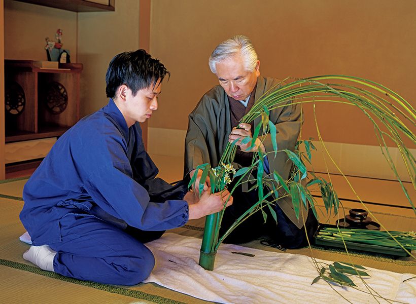 葉付きの青竹花入に柳と根締めの水仙を入れる作業は、二人がかり。若宗匠が花入をしっかり支え、家元が柳の枝を整えながら結んでいく。柳の枝は、点心席となる合ごう親しん亭ていの座敷の床いっぱいに広がる。