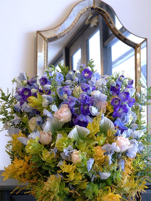百貨店内にある美術画廊で陶芸展を開催するお友達への贈り花を制作しました。スイートピー‘アッシュブルー’、デルフィニウムの‘マーキュリー’と‘アルタイル’の美しい濃淡ブルーに、淡いピンクのバラ‘シフォンベール’とパフィオペディラム‘クレアドルーン’を合わせ、金葉アカシア‘ツトム’の黄色を加えると、爽やかな雰囲気のアレンジに。