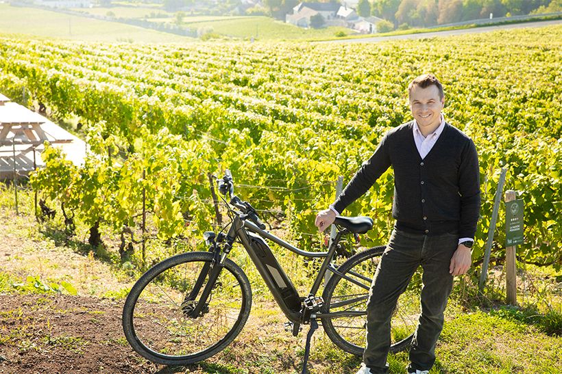 ヴェルテュ村を望むぶどう畑にて、創業者の孫であるステファン・エレゴさん。家族とともに未来を見据える次世代の承継者。電動自転車で巡るワイン観光など、地域を通して、シャンパーニュの魅力を広く伝えている。