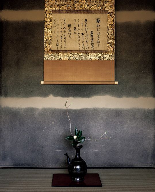 「800年の歳月を経て、里帰りした熊野懐紙」 詠山河水鳥和歌 右近衛大将（源）通親 たにかはのいわまのこけやおしとりのたまものふねのとまりなるらん 旅宿埋火 うつみ火のあたりのみかはかりいをさすかきねのむめも春しらせけり  床に掛かる「熊野懐紙」は、後鳥羽院の熊野詣に随行した源通親の書で、「山河水鳥」「旅宿埋火」の和歌2首がしたためられている。手前の古格を感じさせる水瓶には、春の兆しを告げる土佐水木の枝と白玉椿が入る。