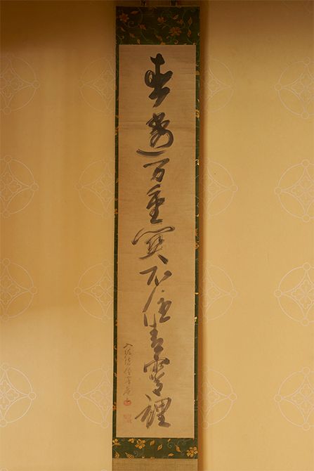 掛け軸「直透万重関　不住青霄裡」は、大徳寺百五十三世澤庵宗彭（たくあんそうほう）禅師の一行書。父である家元や先代も好み、宗家の茶席でしばしば用いられる。若宗匠にとっては修行中に心の支えとなった禅語。禅語録『臨済録』収録。