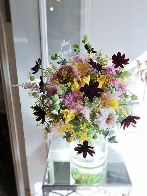 チューリップやふりふりのスカビオサ、ミモザなど、春を感じさせる花を束ねた贈り花です。ピンクと黄色の明るい花色合わせに、チョコレートコスモスのダークな花色でアクセントを加えました。チューリップは‘イエローピクチャー’。ほかにアスチルベ‘ライトピンク’、シレネ‘小布施の郷’などを使用。