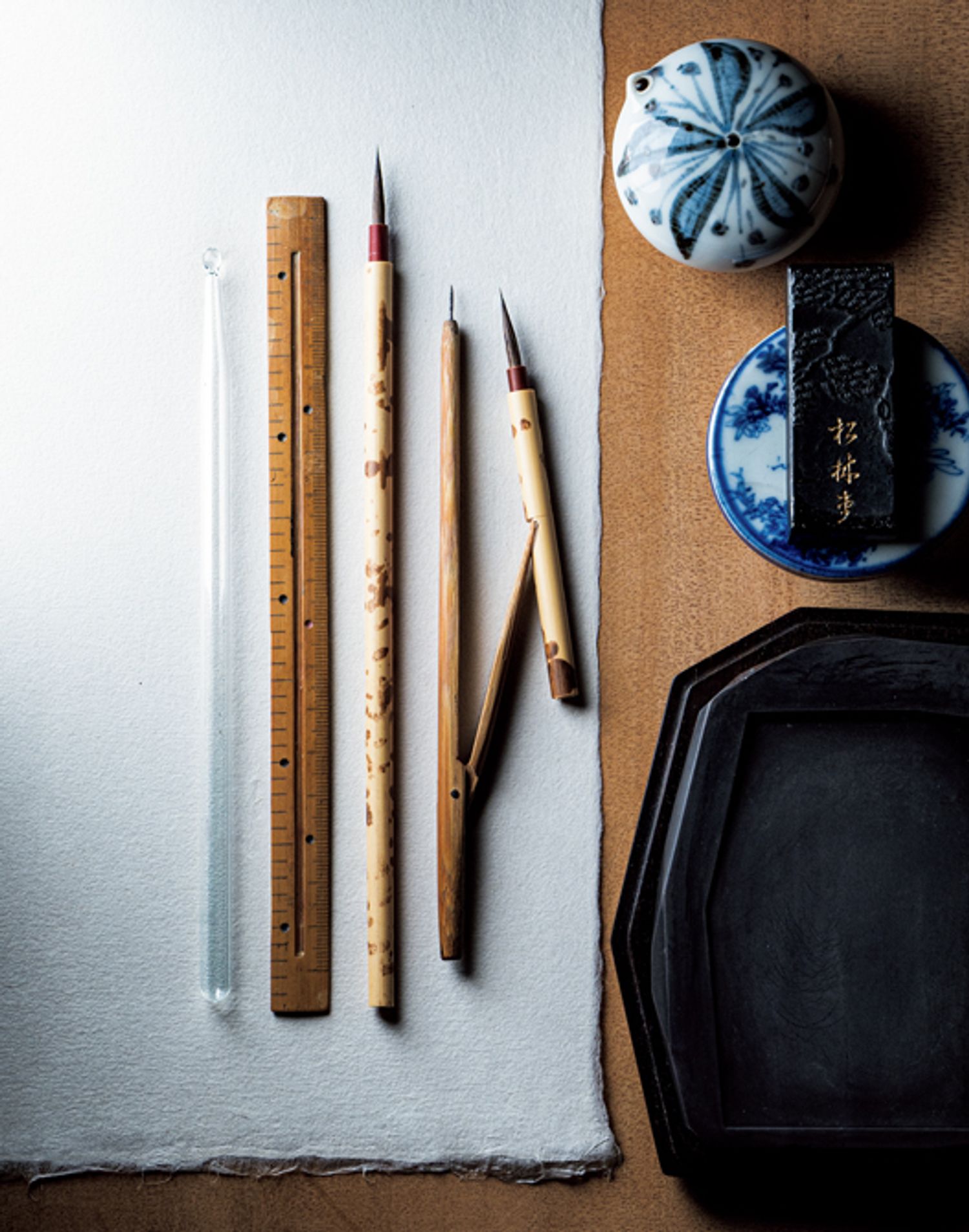 紋を描くための道具。左から、筆と平行に持つことで直線を描く際のガイドとなるガラス棒、溝を彫り込んだ溝引きと呼ばれる定規。きもの地に墨を入れる専用の上絵筆。筆先にはこしのあるイタチと狸の毛を使用。右は、曲線を描くのに必要な、分廻しと呼ばれる竹製のコンパス。