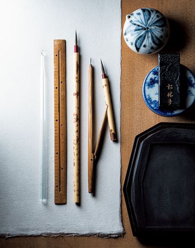 紋を描くための道具。左から、筆と平行に持つことで直線を描く際のガイドとなるガラス棒、溝を彫り込んだ溝引きと呼ばれる定規。きもの地に墨を入れる専用の上絵筆。筆先にはこしのあるイタチと狸の毛を使用。右は、曲線を描くのに必要な、分廻しと呼ばれる竹製のコンパス。