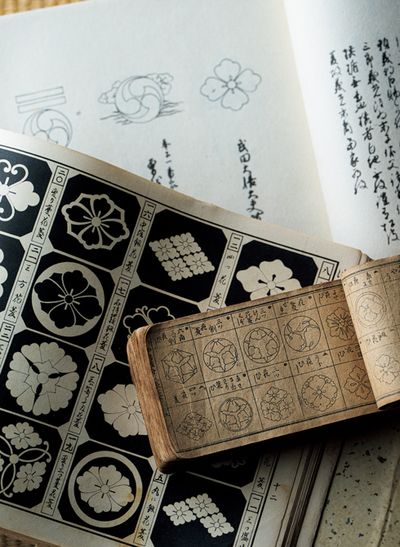 室町期からの紋を新井白石が写した『見聞諸家紋（けんもんしょかもん）』（奥）をはじめ、昭和11年に摺られた『平安紋鑑』（中）、初代の波戸場源次が使っていた冊子（手前）など、古い家紋帳は、波戸場さんたちのデザインのインスピレーション源に。