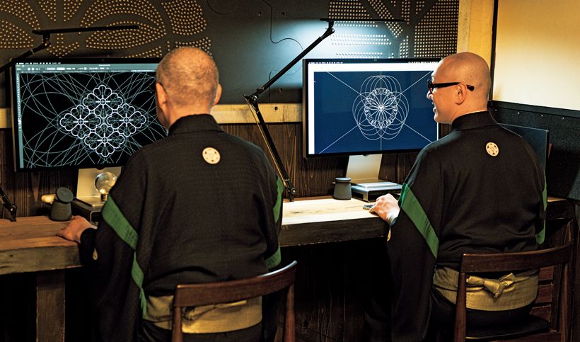 隣り合ってパソコンに向かう父・承龍さん（左）と、息子の耀鳳さん（右）。壁面を飾るのは、太鼓の鋲（びょう）で家紋を表現した工房の代表作「Mon×Studs」。ホテルや商業施設の内装にも採用された。