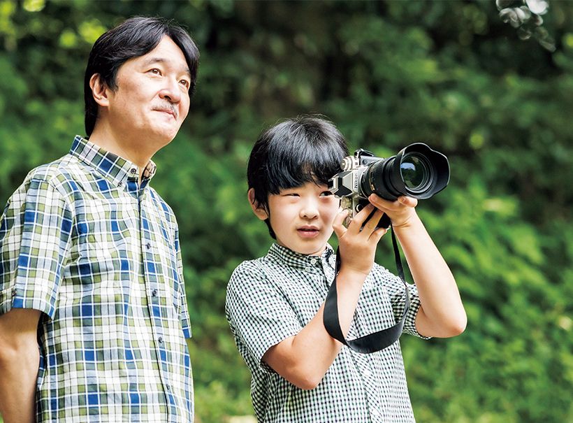 （22）同年8月10日　赤坂御用地にてご散策中秋篠宮皇嗣殿下より一眼レフカメラの使い方を教わる悠仁さま。
