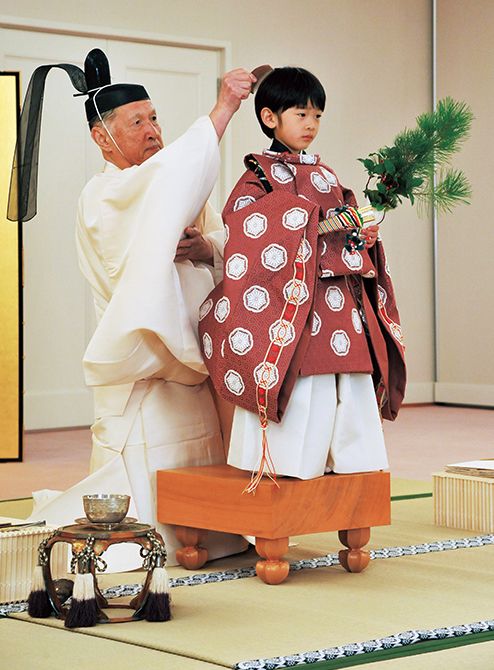 （10）「深曾木の儀」で宮内庁御用掛に毛先を整えてもらっているところ。童形服に身を包み、左手に小松2本と山橘の枝1本、右手に横目扇をお持ちになり、足もとは2つの青石を踏みしめておられる。