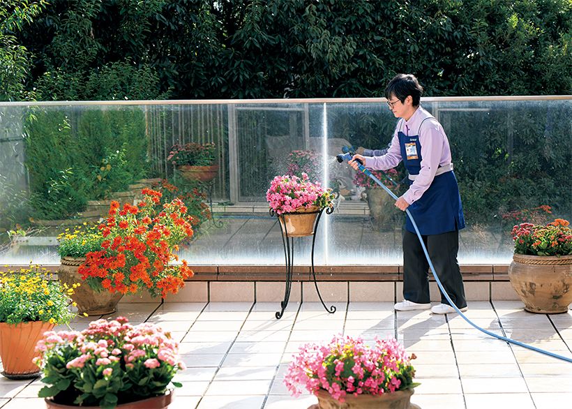 ほうきでタイルの砂やホコリを払った後、ホースで水圧 をかけながら汚れ落とし。その後、タイルブラシで砂 岩タイルの黒ずみや溝の汚れを丁寧にこすり落としま す。そして、手すりの透明パネルの内側をクロスで念 入りに拭き上げた後は、事前の要望に添って枯れた花 がらを摘み取り、プランターの植物に水やりをします。