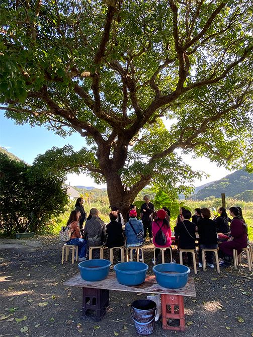 暖かな日差しの中、泥染めについてレクチャーを行う「金井工芸」金井志人さんを囲んで。