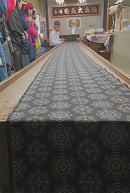 織り上がった反物を、検査員が製品検査を行う様子も見学。織り幅や絣柄の揃い方、色ムラや傷など、24項目におよぶ厳格な審査に合格した反物だけが「本場大島紬」として認められ証紙が貼られます。