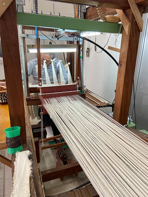 「大島紬は二度織る」といわれており、その一度目が締め機で絣筵（かすりむしろ）を作る工程です。絹糸を木綿の糸で固く締めて織り込むことで、手でくくるのでは再現できない緻密な柄の防染が実現。力と同時に繊細さも要求される高度な仕事です。