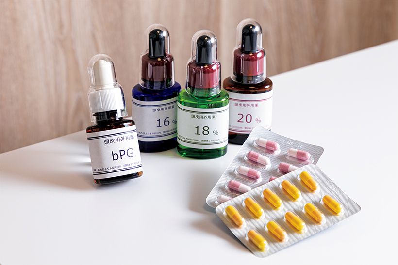 奥は頭皮に塗布するミノキシジル外用薬。すべて院内製剤で、6～20％の7段階がある。手前が内服薬のミノキシジルで、こちらも外用薬と同様に院内処方で細かく濃度が設定されている。内服薬処方の際は別途血液検査（5500円）が必要。