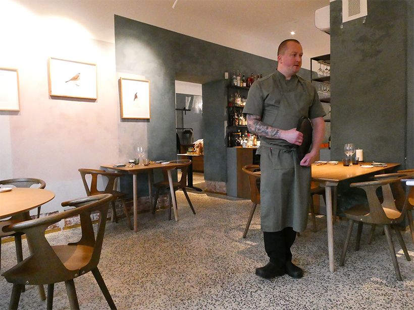 グレーを基調としたシックなインテリアの「パワール・マーヤ」。鳥の細密画が飾られている。料理の説明をする、ヘッドシェフのユリス・ドゥカリスキスさん。