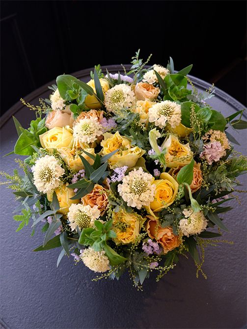 スカビオサ‘ルナ’に、黄色系のバラ3種を合わせたアレンジ。バラは‘レモンフォセット’と‘カタリナ’、‘プリンセスライン’と、ニュアンスが微妙に異なる黄色系を選びました。ほかに切り花では珍しいペチュニアの‘アレグラ’、スターチス‘シースルーホワイト’、ユーカリ、銀葉アカシアを使用。奥様のバースデーにご主人とお子様達からの贈り花です。