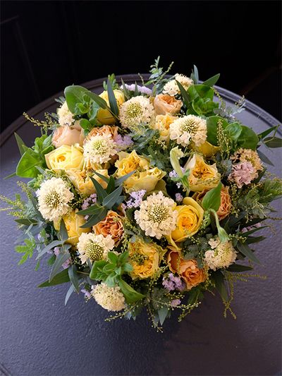 スカビオサ‘ルナ’に、黄色系のバラ3種を合わせたアレンジ。バラは‘レモンフォセット’と‘カタリナ’、‘プリンセスライン’と、ニュアンスが微妙に異なる黄色系を選びました。ほかに切り花では珍しいペチュニアの‘アレグラ’、スターチス‘シースルーホワイト’、ユーカリ、銀葉アカシアを使用。奥様のバースデーにご主人とお子様達からの贈り花です。