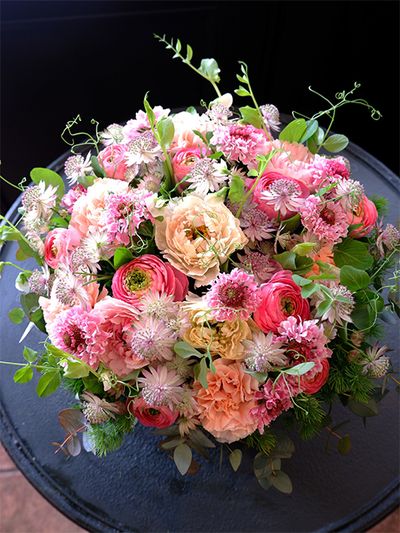 ご友人の息子さんへ、ご結婚のお祝いの贈り花のオーダーをいただき、この時期に出回る花を種類豊富に使い、華やかな雰囲気のアレンジを制作しました。スカビオサ‘シオリ’、ラナンキュラスの‘シャルロット クリーム’と‘ポー’、カーネーション‘シルクミナミ’、アストランティアなどを使用。エンドウマメのつるで動きをつけています。