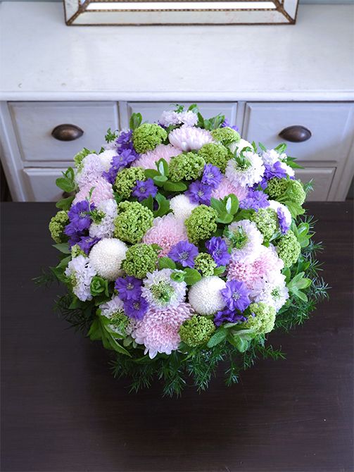 白花の‘ちょんまげ トノ’を使い、涼しげな花色合わせのアレンジを制作。マム‘セイ ヌーベル’とピンポンマム、デルフィニウム‘ラベンダーサファイア’、ビバーナム・スノーボール、アップルミントなどを使用。スカビオサの花心からちょこんと飛び出る葉っぱが楽しさを引き出します。