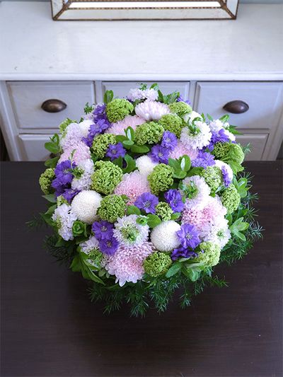 白花の‘ちょんまげ トノ’を使い、涼しげな花色合わせのアレンジを制作。マム‘セイ ヌーベル’とピンポンマム、デルフィニウム‘ラベンダーサファイア’、ビバーナム・スノーボール、アップルミントなどを使用。スカビオサの花心からちょこんと飛び出る葉っぱが楽しさを引き出します。