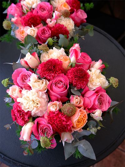 スタンダード系のスカビオサ‘プリエージュ’は何とも鮮やかな紅色！しかも大輪でインパクトがあります。濃淡ピンクのバラ3種と合わせ、華やかなアレンジを制作しました。バラは‘オール4ラブ＋’、‘ビーハイブ’、‘ストロベリーモンローウォーク’を使用。ほかにカーネーション‘バニラミナミ’、ユーカリなどを利用しています。少し早めの母の日ギフトで、ご夫婦から二人のお母様へ。