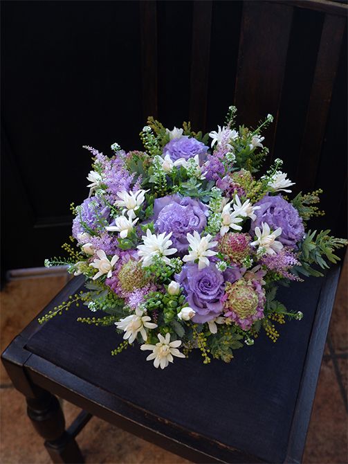 スカビオサ‘ヒマリ’に薄紫の花を合わせ、シックで上品なアレンジに。薄紫はリシアンサス‘NFラベンダー’と染めのアスチルベ‘ラベンダー’。小さな白いカーネーションの‘ミニティア ミルク’を散らして明るさをプラス。タラスピオファリムと銀葉アカシアをあしらいに加えました。スカビオサ‘ヒマリ’の花心の色がナチュラル感を出してくれます。