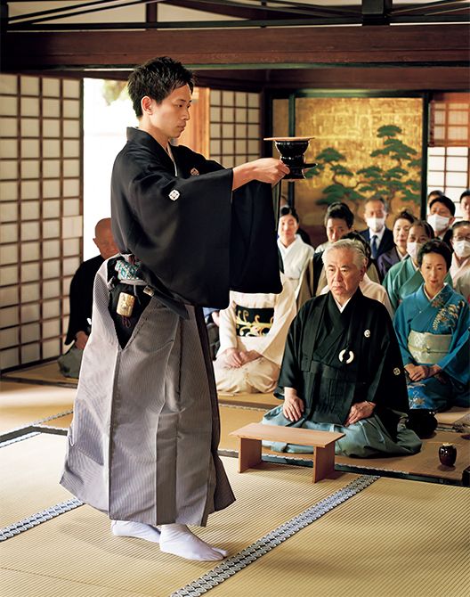 2025年5月に大徳寺塔頭孤篷庵で行われた「遠州忌茶会」で伴頭を務める若宗匠。厳かな空気の中でお茶を運ぶ若宗匠を、参加者が静かに見守っている。伴頭は天目台と呼ばれる台の両脇を持ってお茶を運ぶ。