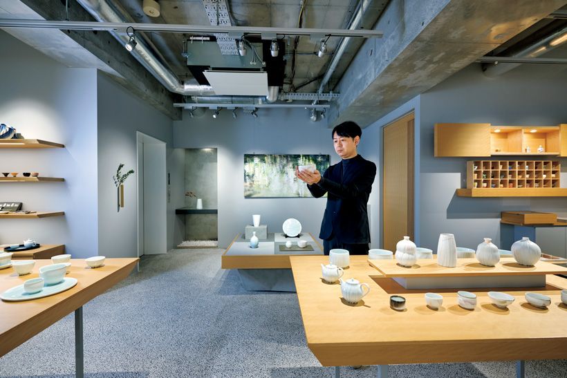 明るく広々としたHULS Gallery Tokyo店内。取材時に個展を開催中だった樽田裕史さんの作品を手にする、代表の柴田裕介さん。