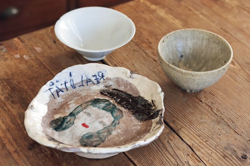 左奥から時計回りに、個を抑えた中に品格を宿す「青白磁輪花鉢」磯松大悟 作（径14 × 高さ5.5センチ）6600円　作家自ら掘り出す原土で作る「黄釉飯碗」平瀬アスカ作（径12×高さ7センチ）4400円　リトアニア出身の作家が確立させた独特の作風に心躍る「女性図台皿」チュパセルゲイ 作（21 × 22.5 × 高さ5.5センチ）2万2000円