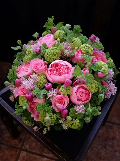 ご両親から娘さんへ、結婚祝いの贈り花を。ピンクとフレッシュグリーンの花色合わせで、かわいらしいながらもパッと目立つアレンジを制作しました。この時期に出回るシャクヤクのボリューム感と、セアノサス‘マリーサイモン’の繊細さ。これはとても相性のよい組み合わせだと感じます。シャクヤクは‘エッチドサーモン’を使用。ほかにバラ‘ブロッサムピンク’、クレマチス‘天使の首飾り’を合わせ、濃淡ピンクの花色合わせにしました。みずみずしい緑色は、ビターチョコゼラニウムとビバーナム・スノーボールです。