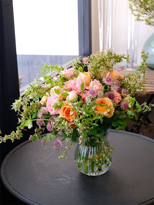 お客さまを迎えるご自宅の花飾りのオーダーをいただき、コデマリ‘ピンクアイス’をたっぷり使ったブーケを制作しました。ピンクのバラ‘ジェントルフロウ’とオレンジ色のバラ‘ビーハイブ’をメインに、シャクヤク‘ルーズベルト’、アストランティア‘ローマ’などを加えた華やかな花色合わせですが、コデマリ‘ピンクアイス’を加えると、ぐっとナチュラルな雰囲気に。動きのあるエンドウマメのつるも加えました。