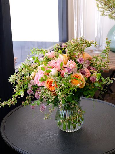 お客さまを迎えるご自宅の花飾りのオーダーをいただき、コデマリ‘ピンクアイス’をたっぷり使ったブーケを制作しました。ピンクのバラ‘ジェントルフロウ’とオレンジ色のバラ‘ビーハイブ’をメインに、シャクヤク‘ルーズベルト’、アストランティア‘ローマ’などを加えた華やかな花色合わせですが、コデマリ‘ピンクアイス’を加えると、ぐっとナチュラルな雰囲気に。動きのあるエンドウマメのつるも加えました。