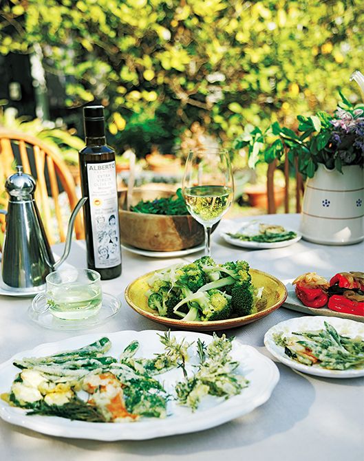 緑に囲まれた自宅の庭のテーブルに並ぶ光世さんお手製の料理はすべてオリーブオイルを使う。手前から「ハーブと夏野菜のオリーブオイル天ぷら」、「ブロッコリーのオリーブオイル煮」、「赤ピーマンと炒め玉ねぎソース」。