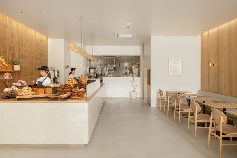 温かみある店内のデザインは、国内外で活躍する芦沢啓治建築設計事務所が担当。小麦粉の質感をイメージしたカウンターや、パンの焼き色を思わせる手焼きタイルなど、パンを連想させる意匠が随所に施されている。 