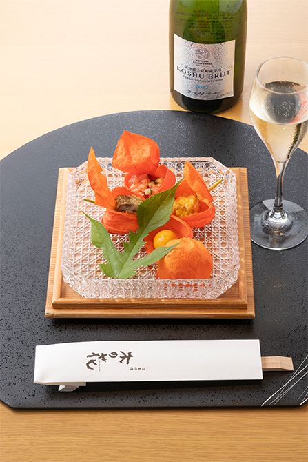 前菜は、ほおずきの中に、ほおずきの実を模した南京、揚げとうもろこし、蛸梅肉和えと泉州水茄子、鯵酢〆寿司。「信州 富士見町産 甲州 ブリュット 2022」とともに。