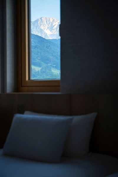 「ジュニアスイート北アルプスビュー」のベッドルームから望む、朝日に照らされた白馬の山々。窓枠がまるで絵画の額縁のように、美しい景色を切り取る。