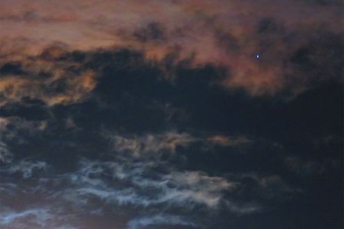 輝く月の周りに広がる淡い虹色の彩雲。月が明るい夜に探してみて