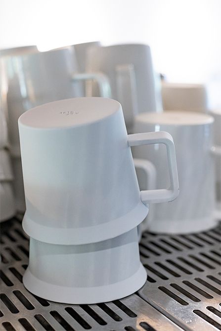 KAIKOU COFFEEにて、コーヒーマシンの上に重ねて置かれたコーヒーカップ。ハンドルは、どんな人でも持ちやすいよう細身に作られている。