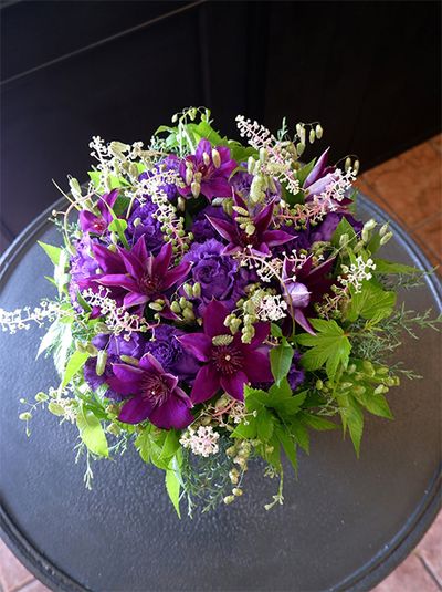 一重咲きの大輪花‘ザ・プレジデント’は、1873年にイギリスで生まれた銘花。鮮やかな紫色の美しさは、現在でも人気があります。その‘ザ・プレジデント’を主役にしたアレンジです。加えた花はリシアンサス‘NFリローラ’の青紫のみ。ヨウシュヤマゴボウ、穂が美しいブリザ・マキシマ、キイチゴ‘ベビーサンズ’などの葉色と対比させ、シンプルながらゴージャスな印象に仕上げました。