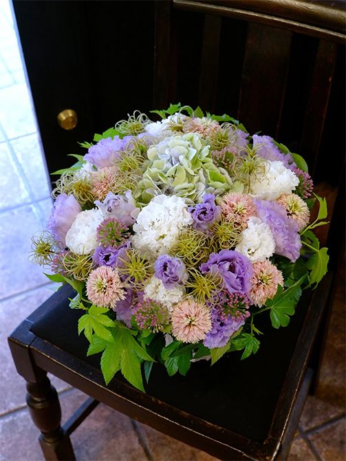 クレマチスは初夏の花後にタネをつけます。くるくる巻きの形状がユニークで、切り花でも人気となっています。そのクレマチスシードをアクセントにしたアレンジがこちら。リシアンサスの‘ボヤージュスノー’と‘NFラベンダー’、アジサイ‘ベレナアンティークブルー’、エキナセア‘チェリーフラッツ’、アリウム‘サマービューティー’、キイチゴ‘ベビーハンズ’などを利用。花と花のすき間を埋めるようにクレマチスシードを加えると、優しいパステルカラーでありながら、大人っぽい雰囲気に仕上がります。