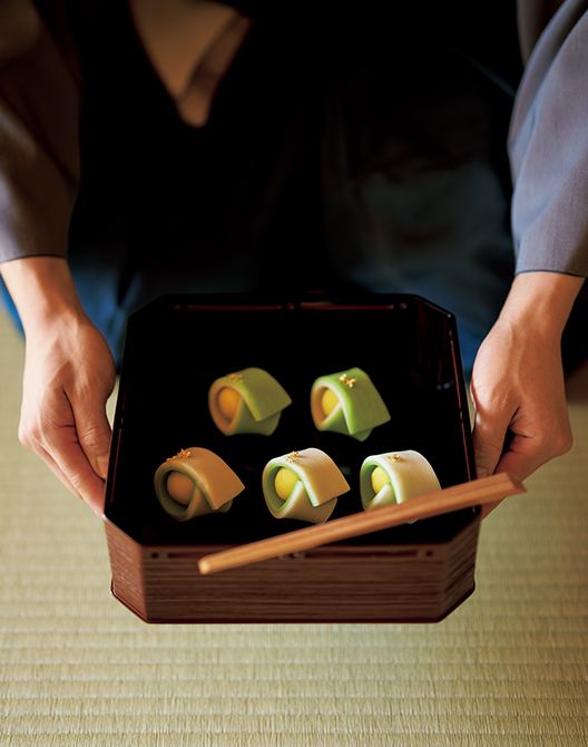 自作の主菓子「玩月」を縁高（ふちだか）に盛りつけて出す若宗匠。「小堀遠州が設計した大徳寺孤篷庵の茶室『忘筌（ぼうせん）』の点前座の唐紙に描かれた波を千筋模様で表し、苔むした清流のイメージで生地を緑色に染め、満月をかたどって黄色く染めた生地を包みました。表面には金箔を飾り、水面に映る月の輝きを表現しています」と若宗匠。